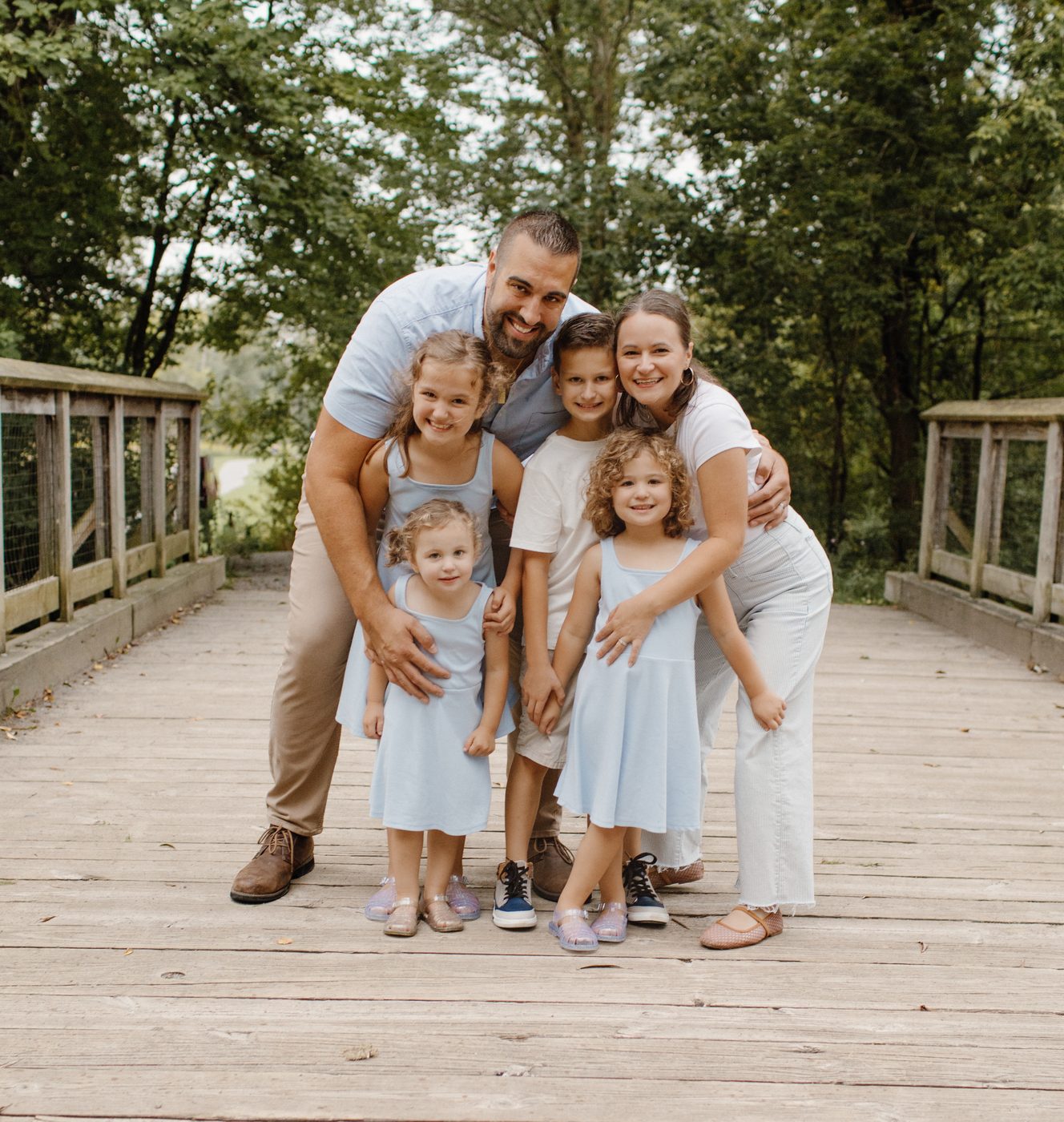 Family of six together on a wooden footbridge at golden hour — Home Team Photography