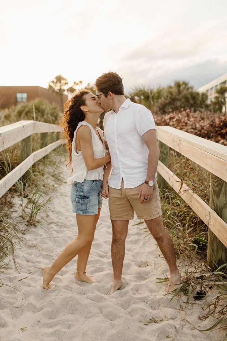 Couple sharing a kiss on a sandy beach path at golden hour — Home Team Photography