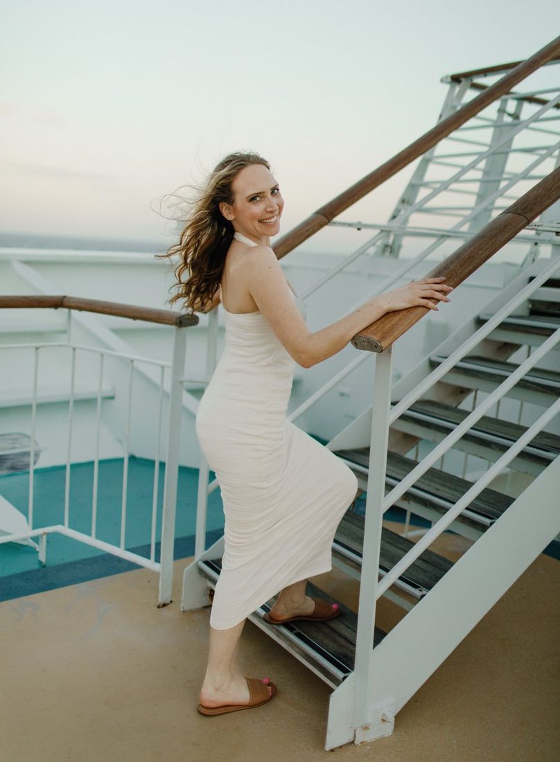 Senior portrait of a young woman in a white dress on a waterfront staircase — Home Team Photography