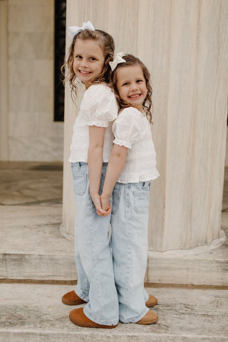 Two young sisters in coordinated white outfits — Home Team Photography