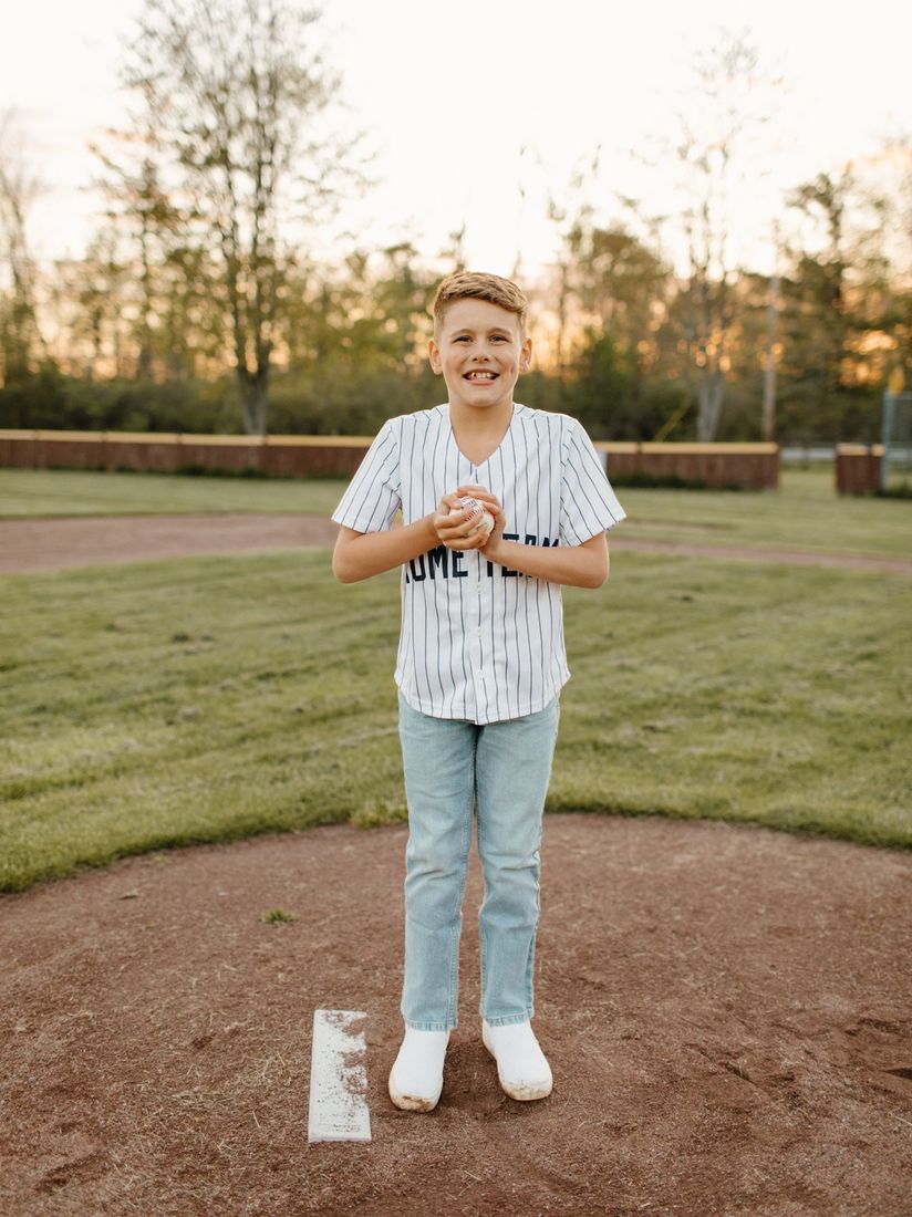 Young baseball player standing on the field at golden hour — Home Team Photography