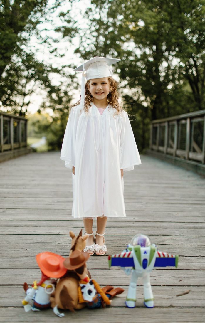 Young girl in a graduation cap and gown with her toys — Home Team Photography
