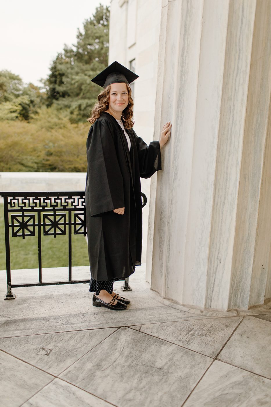 Graduate in cap and gown beside stone columns — Home Team Photography