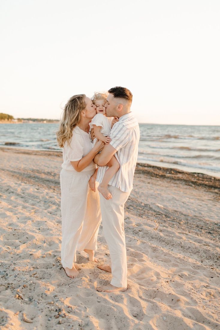 Family at golden hour on a Western New York beach — mom and dad kissing their toddler's cheeks — Home Team Photography