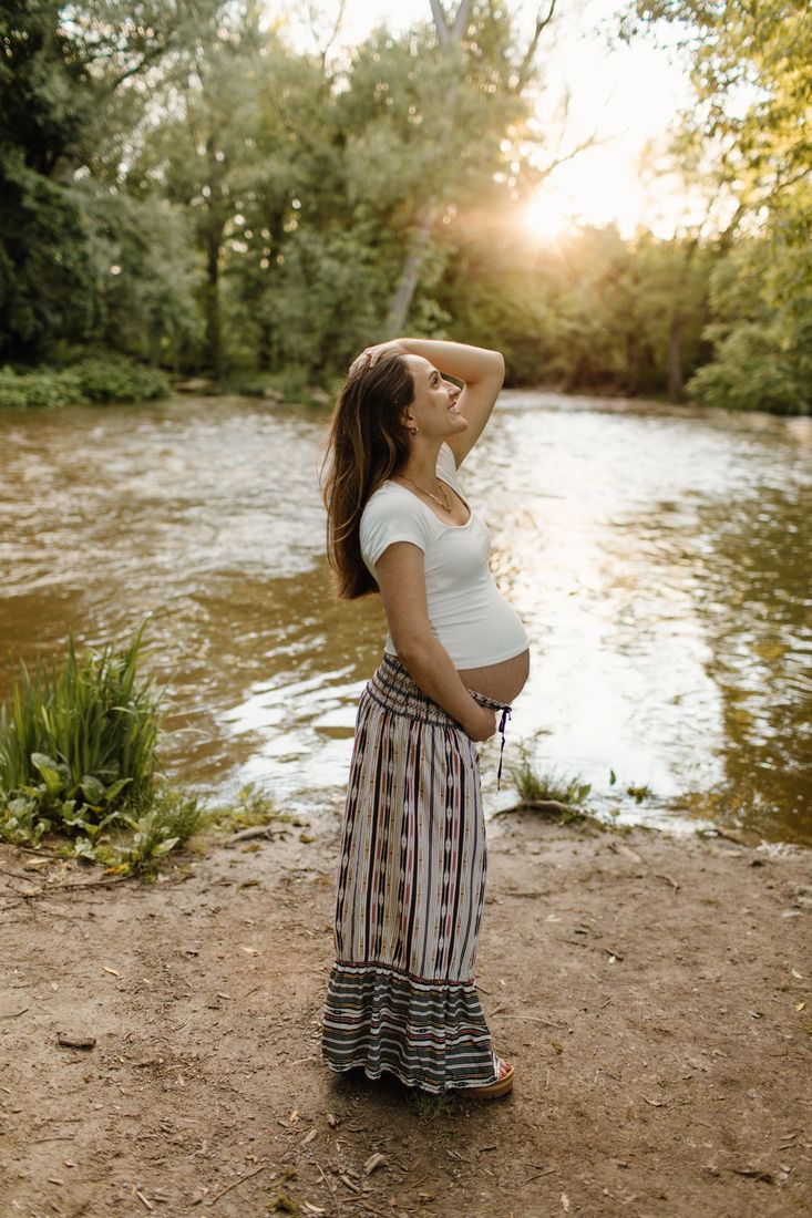 Expectant mother by the river at golden hour — maternity portrait by Home Team Photography
